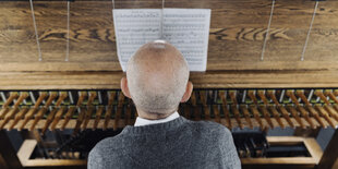 Jeffrey Bossin, Carillonneur des Carillon Berlin-Tiergarten, haut in die Tasten und ist dabei von hinten zu sehen