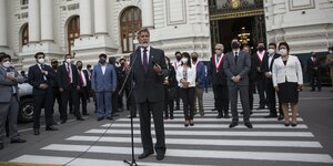 Weißbärtiger Mann steht hinter Mikrofon for Parlamentsgebäude
