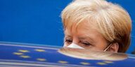 Angela Merkel vor einem Autodach in dem sich die Europaflagge spielgelt.