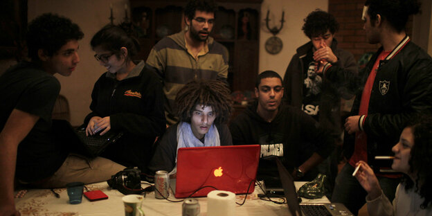 In einer Wohnung sind eine gruppe Jugendliche am Tisch mit Laptops