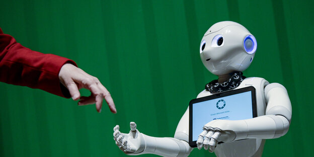 Ein menschlich aussehender Roboter reicht einer menschlichen Hand die Hand