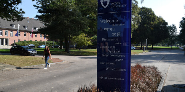 Eine Studentin geht an dem Wilkommensschild am Haupteingang der Jacobs University vorbei.