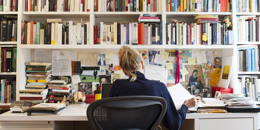 Die Schriftstellerin Siri Huvstedt an ihrem Schreibtisch in Brooklyn NY. Vor ihr eine volle Bücherwand