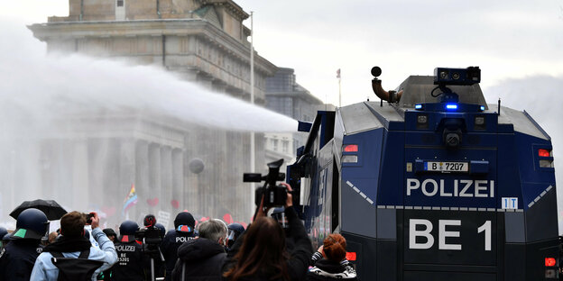 Wasserwerfer der Polizei fahren bei einer Demonstration gegen die Corona-Einschränkungen der Bundesregierung zwischen dem Brandenburger Tor und dem Reichstagsgebäude auf.