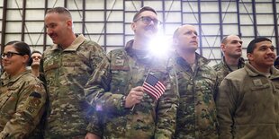 Eine Gruppe von amerikanischen Soldaten und Soldatinnen, einer hält ein US-Fähnchen