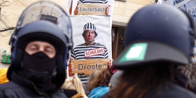 Plakat zeigt den Virologen Dr. Christian Drosten in Straeflingskleidung auf einer Demonstration.