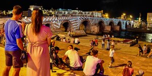 Menschen betrachten LIchtinstallation auf einer Brücke bei Nacht