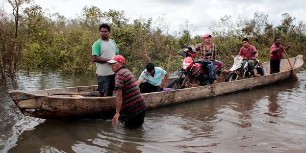 Mehrere Menschen sitzen in einem kleinen Holzboot