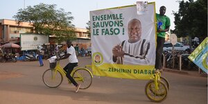 Menschen ziehen mit einem Wahlplakat durch die Straßen von Ouagadougou