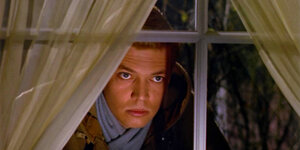 Ein Mann blickt stoisch durch ein Fenster im Film "Peeping Tom" von 1960