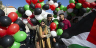 Menschen mit Luftballons in den Farben der Palästinensischen Fahne