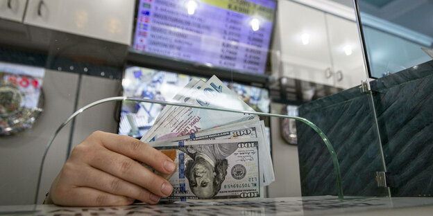 Eine frau hält in einer Wechselstube in Ankara Dollar und Türkische Lira Geldscheine in der Hand.
