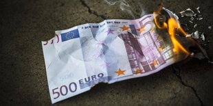 Eun 500 Euro Schein liegt auf dem Boden und brennt