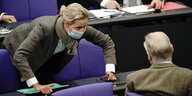 Alice Weidel bückt sich über einen Tisch im Bundestag zu Gauland runter