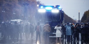 Teilnehmer einer Demonstration gegen die Corona-Einschränkungen der Bundesregierung stehen auf der Straße des 17. Juni vor einem Wasserwerfer. Ein Foto vom 18.11.2020