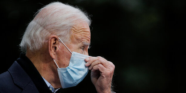 Joe Biden im Profil mit Mund-Nasen-Schutz, er fasst sich an die Nase