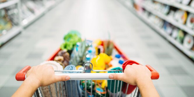 ein Einkaufswagen,wird zwischen den Regalen eines Supermarkts geschoben