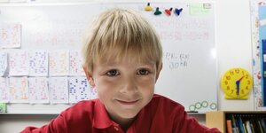 Ein Junge sitzt im Klassenzimmer und lächelt