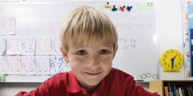 Ein Junge sitzt im Klassenzimmer und lächelt