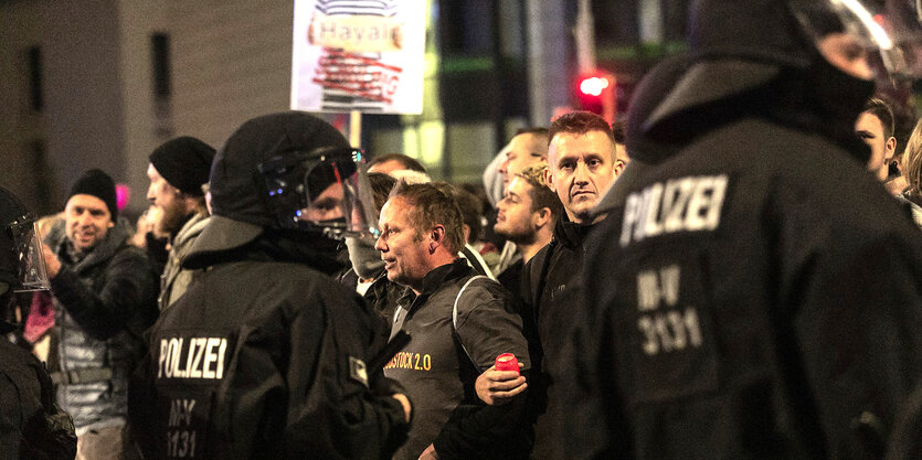 Demonstranten ohne Maske stehen vor einer Polizeikette