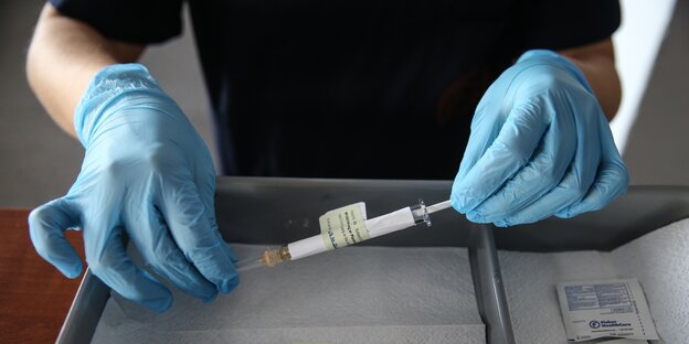 Zwei Hände halten eine Spritze mit künftigem Corona-Impfstoff