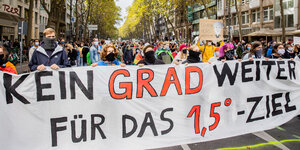 Auf einer Demonstration laufen AktivistInnen eine Straße entlang und tragen ein Banner mit dem Titel: Kein Grad weiter. Für das 1,5-Grad-Ziel.