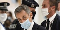 Nicolas Sarkozy mit Mundschutz vor Polizeibeamten.