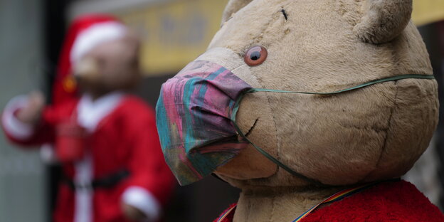 Als Weihnachtsmänner verkleidete Plüsch-Teddybären mit Mund-Nasenschutz