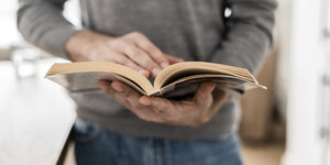 Ein Mann hält ein Buch in den Händen.