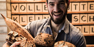 Ein grinsender Mann mit Bart, der mehrere Brote hochhält