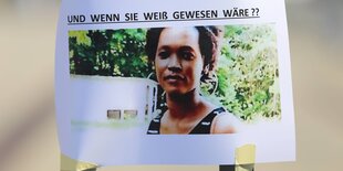 Ein Foto von Rita Awour Ojunge und der Überschrift Und Wenn Sie Weiß Gewesen Wäre klebt an einem Gitter während einer Women in Exile Kundgebung