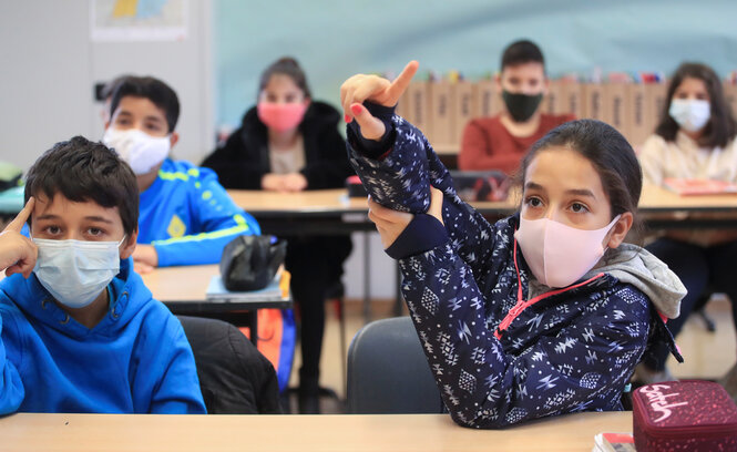 Schüler und Schülerinnen mit Mundschutzmasken in einem Klassenraum