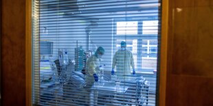 blick durch ein rolloverhängtes Fenster in ein Intensivkrankenzimmer