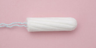 Ein ausgepackter Tampon auf rosa Grund