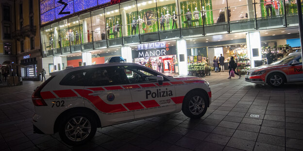 Polizisten gehen vor dem Kaufhaus Manor an der Piazza Dante im schweizerischen Kanton Tessin.