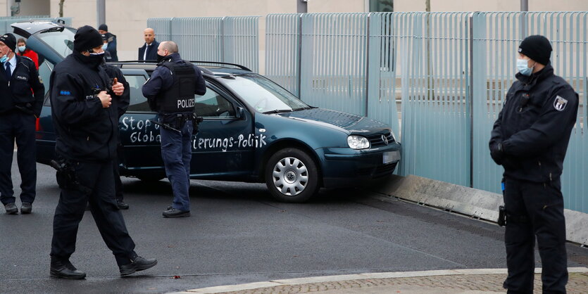 Auto und Polizistzen stehen vor zerbeultem Zaun