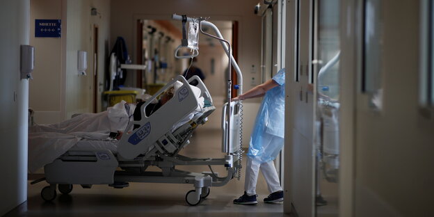 Eine Krankenschwester zieht ein Krankenhausbett über einen Flur in einem Krankenhaus in Paris. Im Bett liegt eine Patientin, die am Coronavirus erkrankt ist.