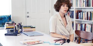 Miranda July sitzt an ihrem aufgeräumten Schreibtisch.