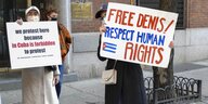 Zwei Menschen tragen englischsprachige Schilder mit der Forderung nach Freilassung von Denis Solis