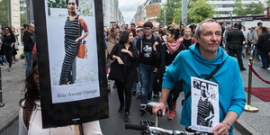 Viele Protestierende laufen mit Schildern durch Berlin: Zwei Tragen Fotos der verstorbenen Rita Ojungé