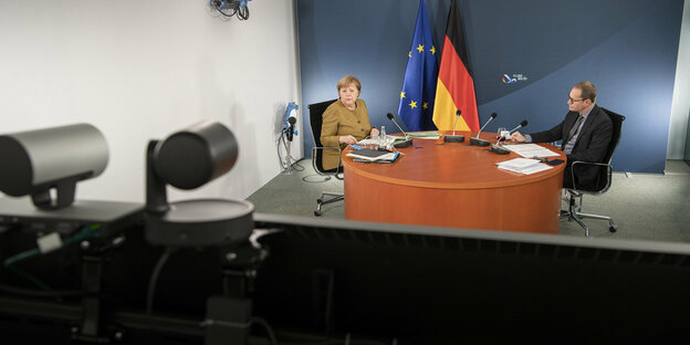 Merkel und Müller an einem Tisch vor einer Deutschlandfahne