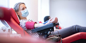 Eine Frau liegt im Blutspendezentrum des Deutschen Roten Kreuzes auf einer Liege und spendet Blut