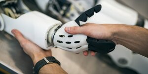 Ein Student der Beuth Hochschule für Technik Berlin arbeitet mit dem modularen humanoiden Roboter Myon