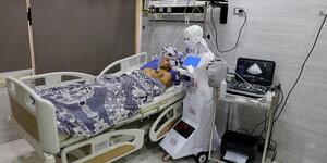 Ein Roboter untersucht einen Patienten im Krankenbett