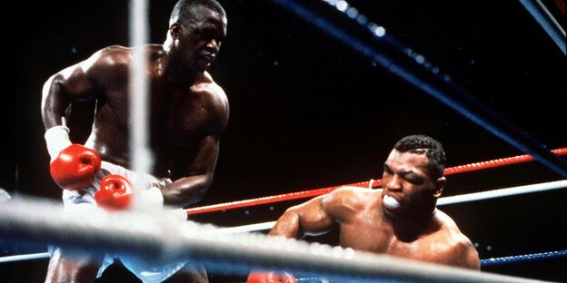 Boxer Mike Tyson taumelt zu Boden, sein Gegner beobachtet ihn dabei
