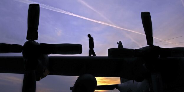Ein Soldat läuft während des Sonnenuntergangs über die Tragflächen eines Militärflugzeeugs auf der Militärbasis der U.S. Airforce in Ramstein