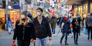 Passanten mit Schutzmasken gehen ueber die weihnachtlich geschmueckte Kortumstrasse, der Haupteinkaufsstrasse in der Fussgaengerzone Bochum