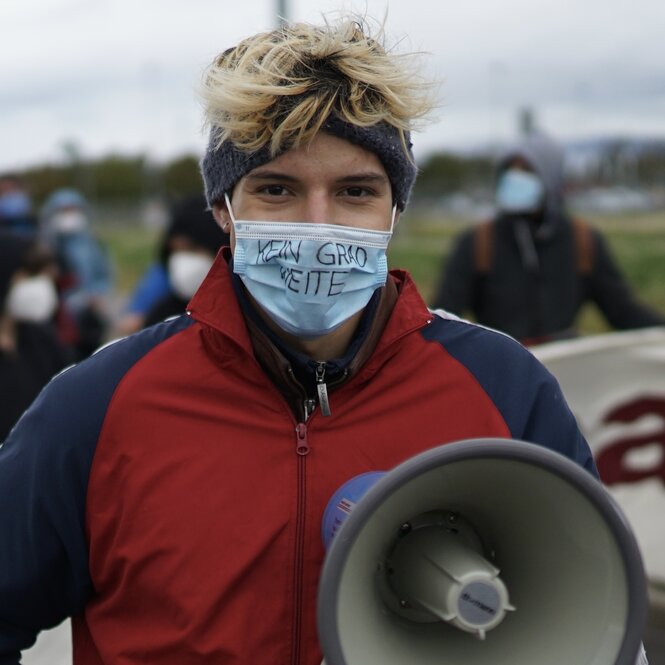 Lukas Gress trägt eine Maske und ein Megafon