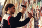 Ein junger Mann haut mit Hammer und Meißel Betonstücke aus der Mauer