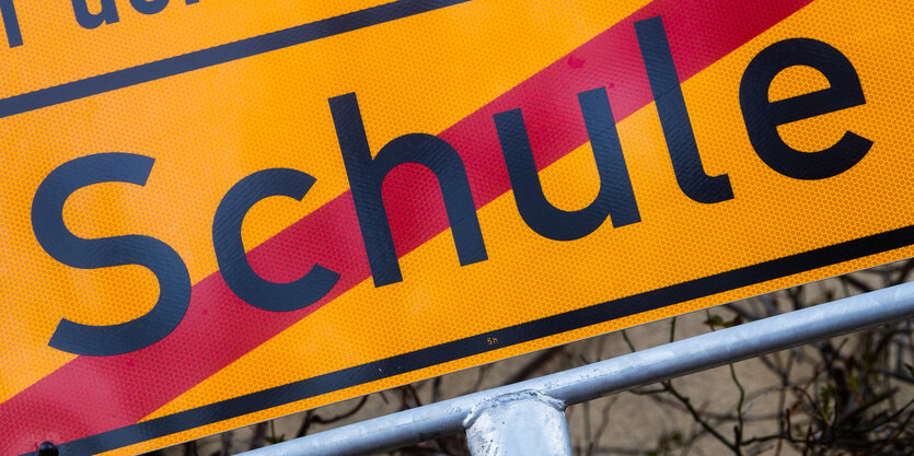 Ein Ortschild, darauf durchgestrichen Schule